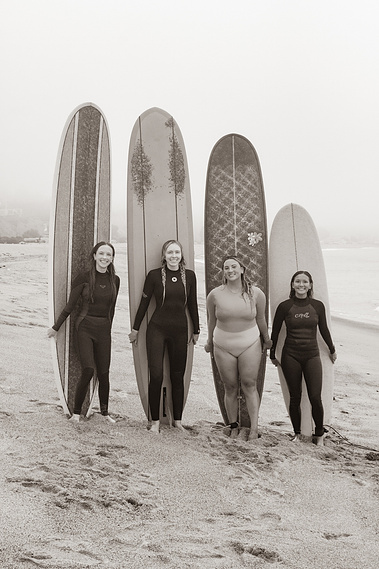 Friends posing with surfboards at the beach. 