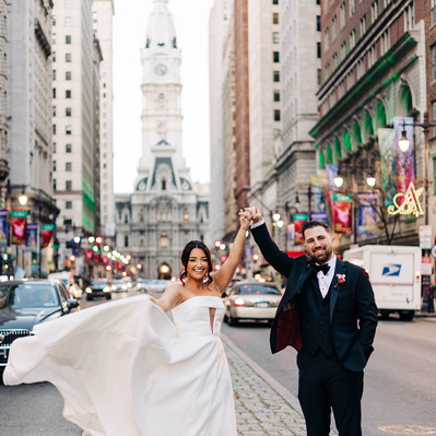 Bride and groom dance on Broad Street in front of City Hall in downtown Philadelphia for their wedding photos