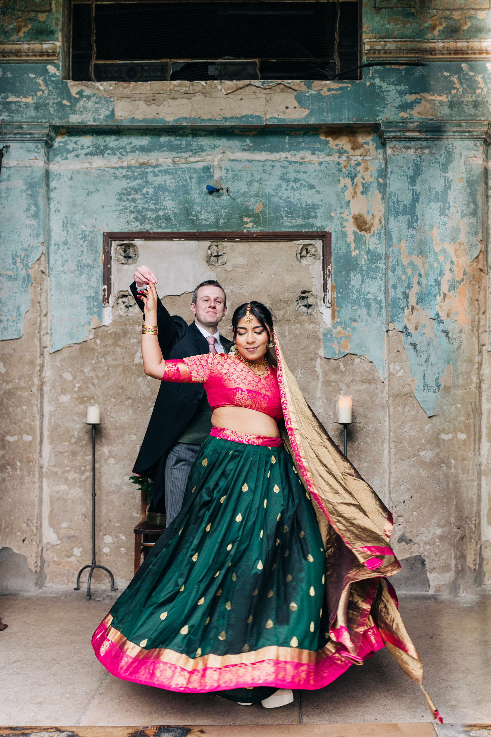 colorful multicultural british indian wedding at asylum chapel in london england UK wedding bride wearing hot pink and emerald green sari from nalli silks groom wearing suit from moss bros