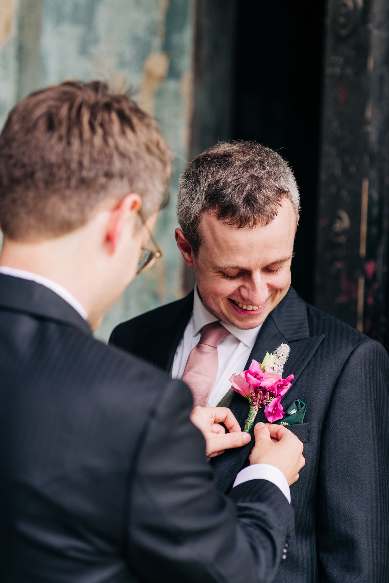 Groom getting ready wedding photos brother of the groom pinning boutonniere