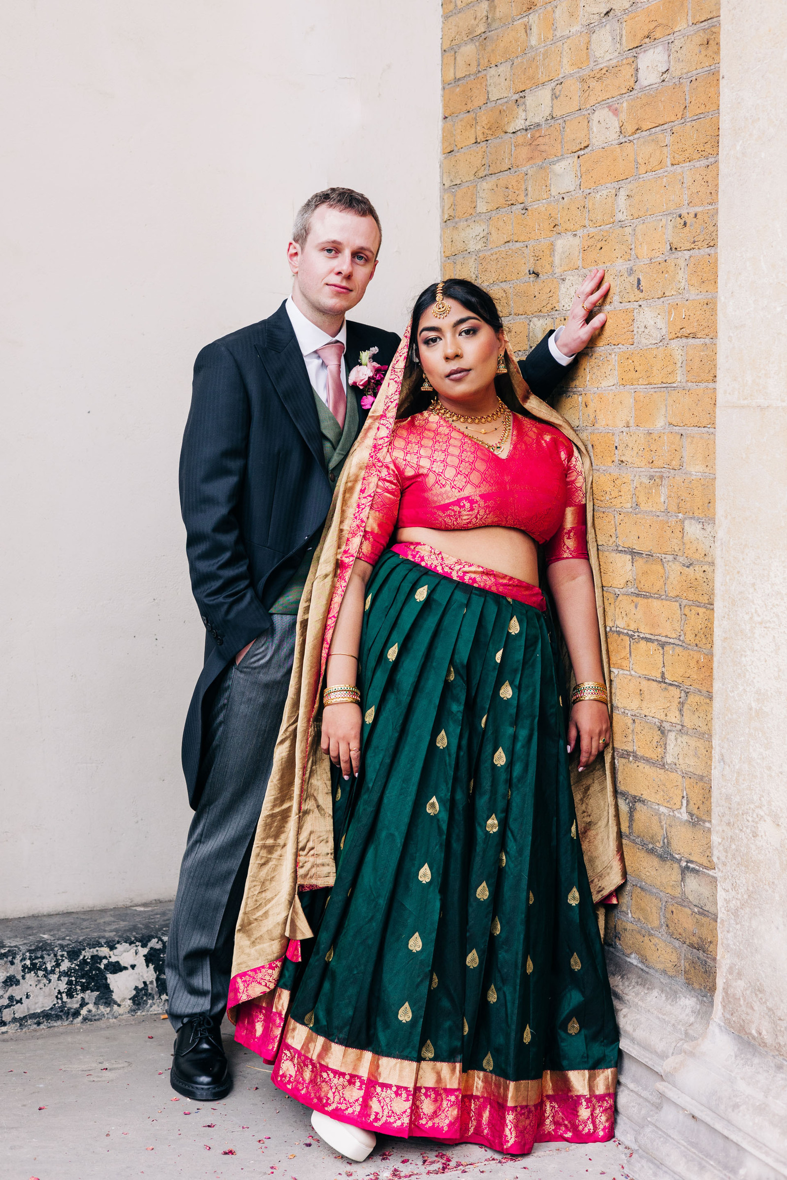 colorful multicultural british indian wedding at asylum chapel in london england UK wedding bride wearing hot pink and emerald green sari from nalli silks groom wearing suit from moss bros
