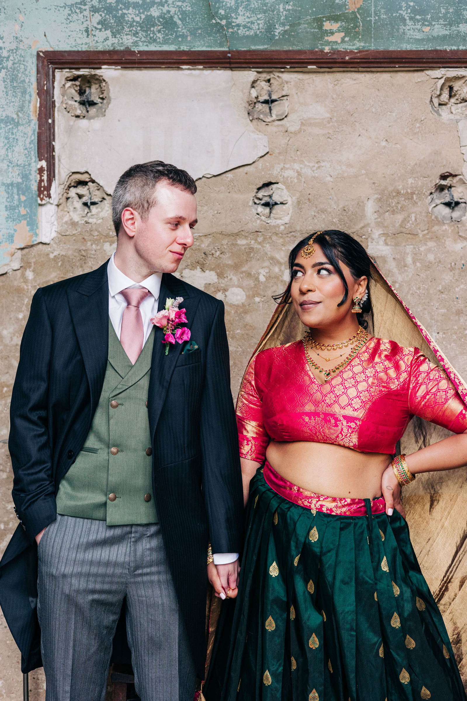 colorful multicultural british indian wedding at asylum chapel in london england UK wedding bride wearing hot pink and emerald green sari from nalli silks groom wearing suit from moss bros