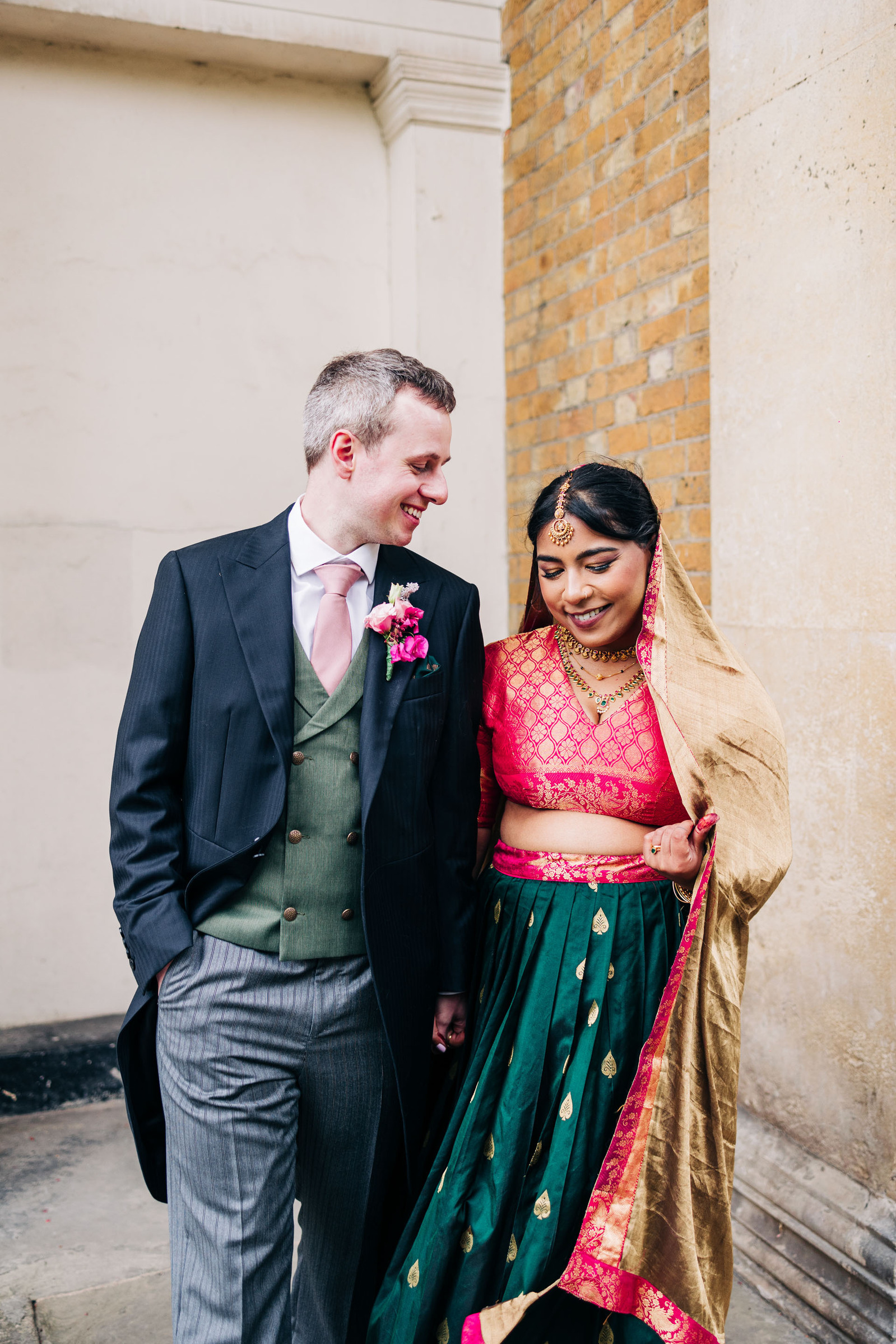 colorful multicultural british indian wedding at asylum chapel in london england UK wedding bride wearing hot pink and emerald green sari from nalli silks groom wearing suit from moss bros