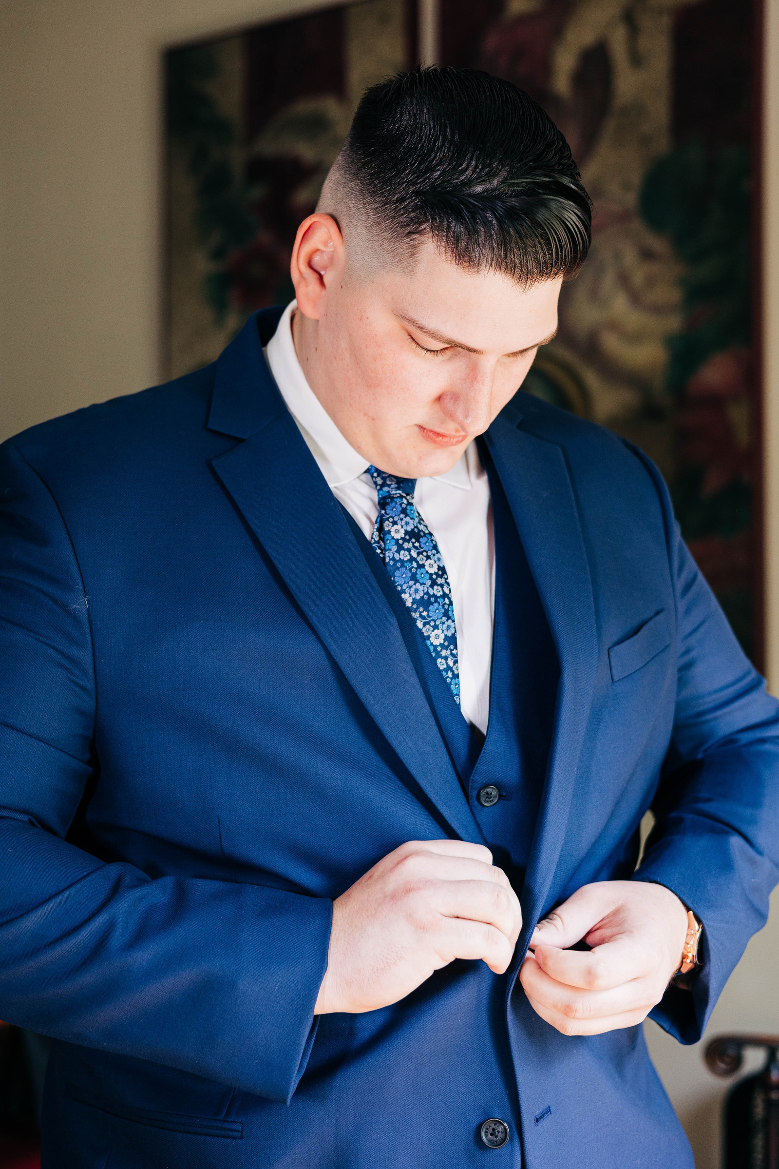 groom getting ready on wedding day wearing blue suit