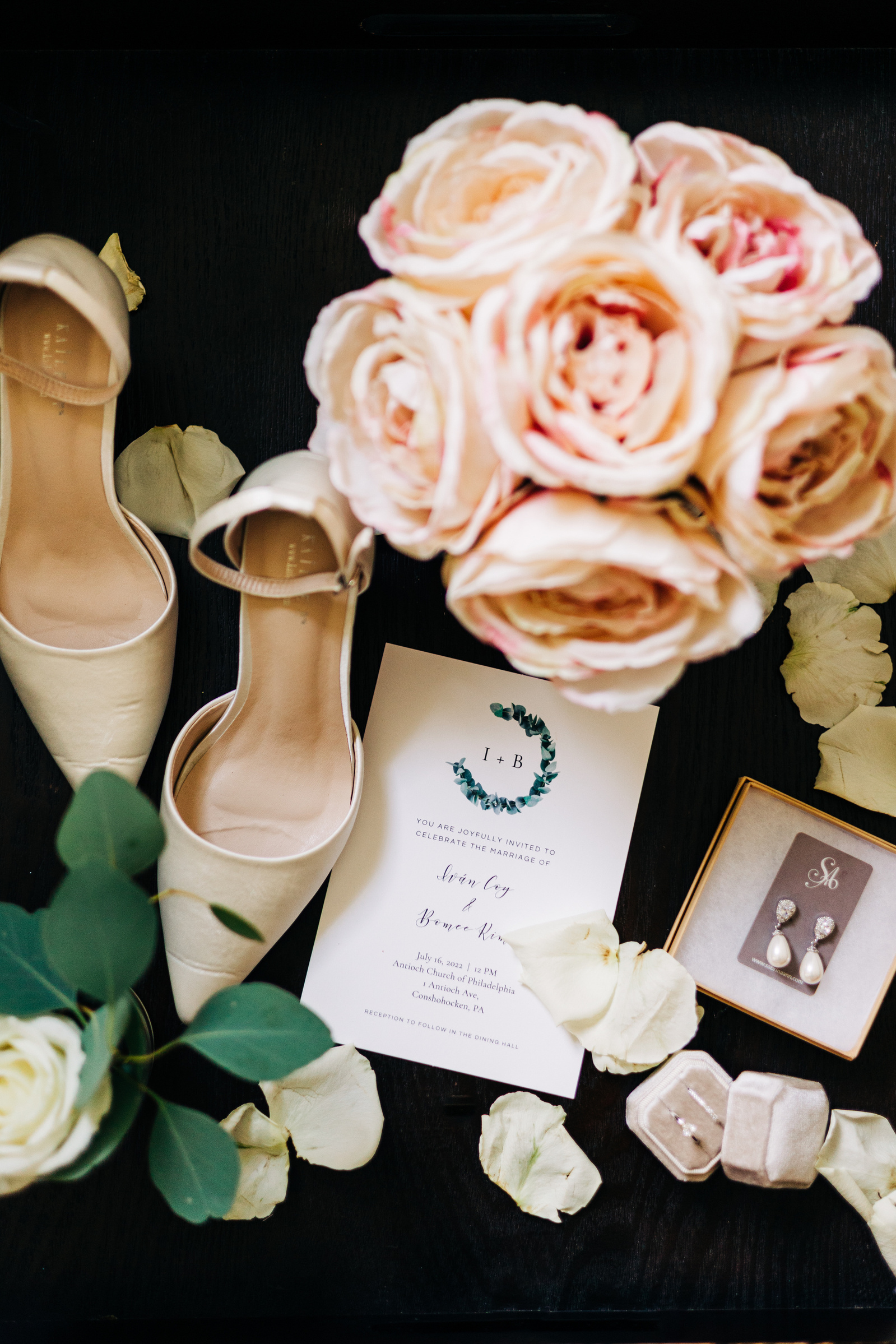 bridal wedding details flat lay featuring invitation, flowers and shoes