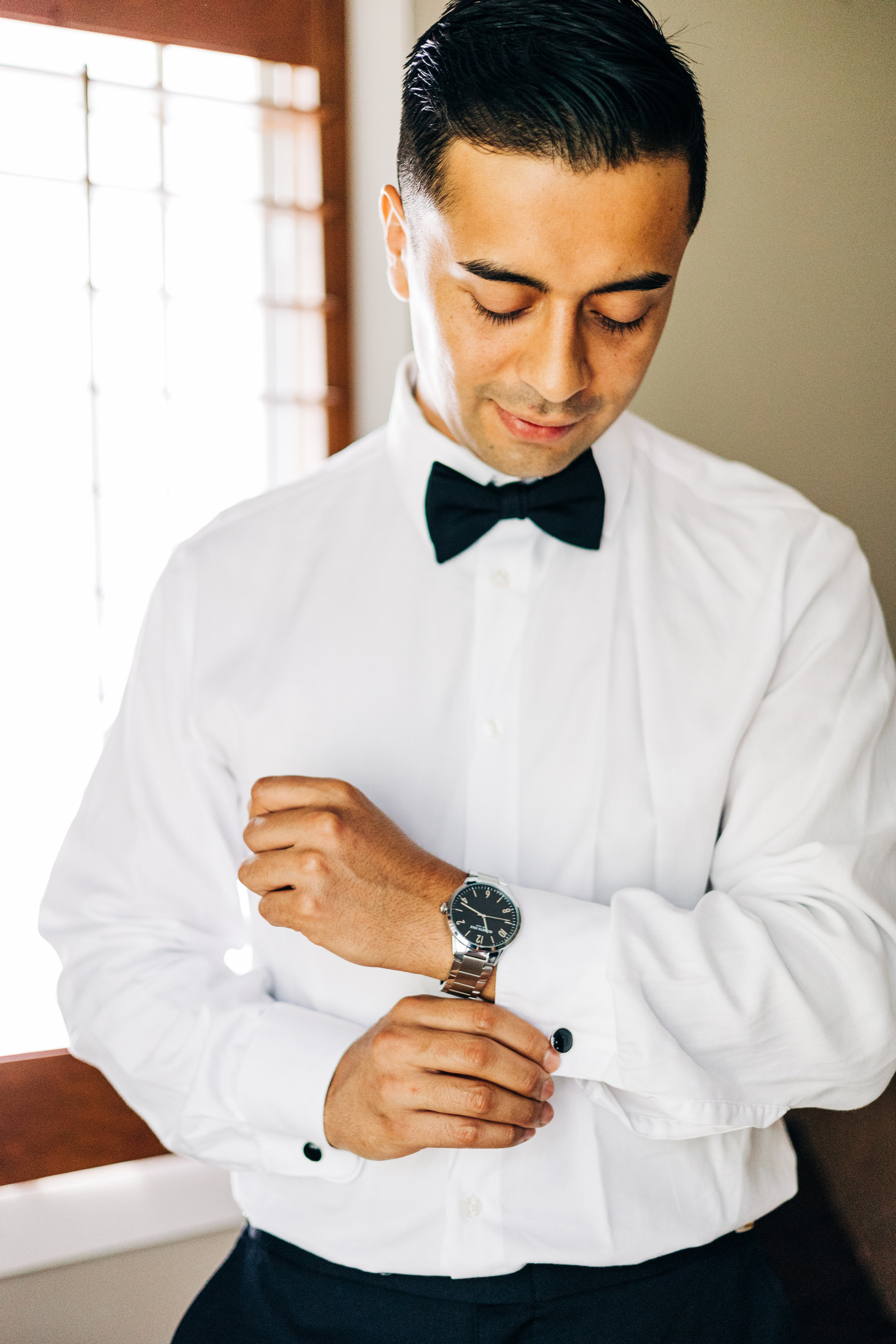 groom adjusting his watch while getting ready for his wedding