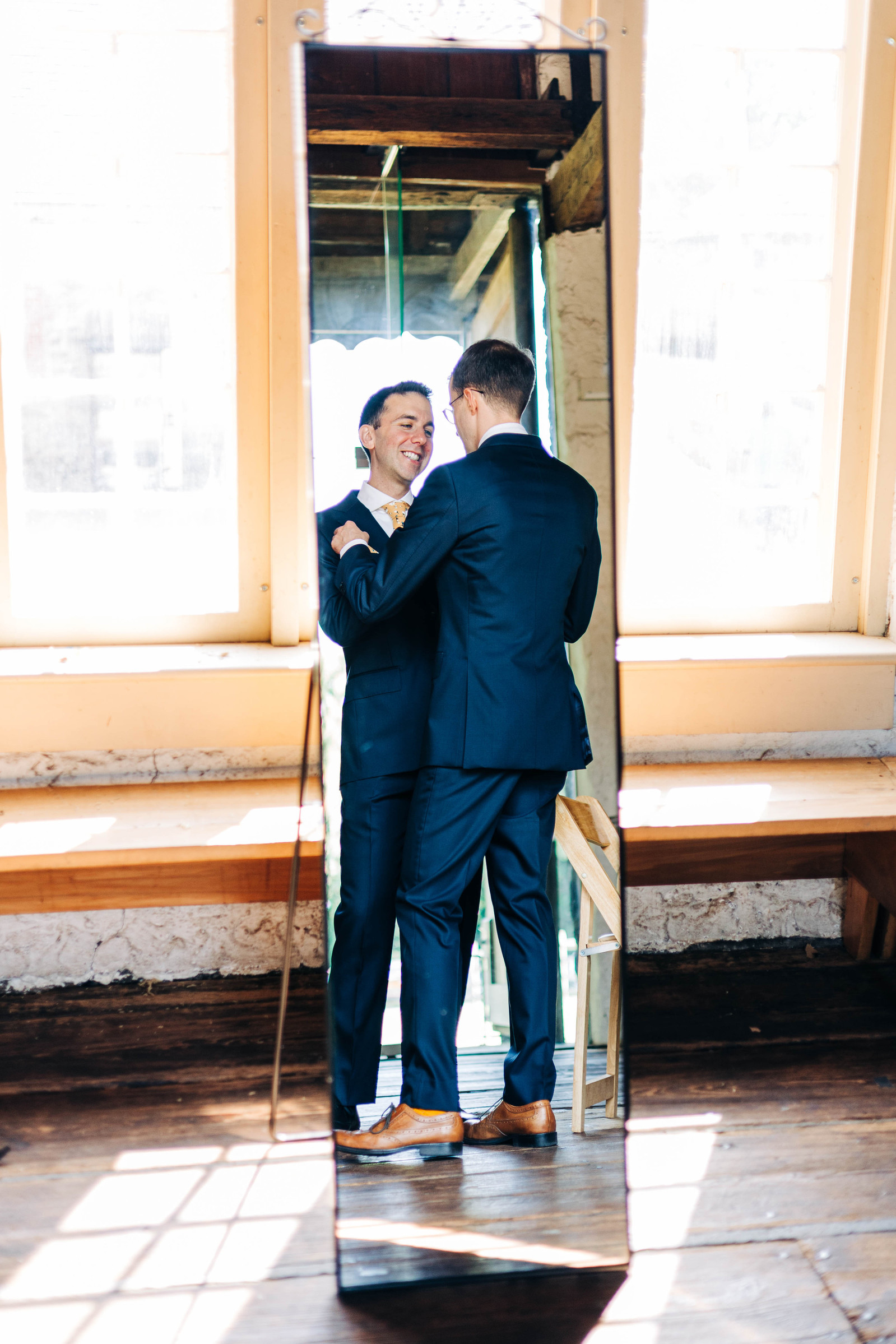 two grooms getting ready together on their wedding day in the suite at bartram's garden in philadelphia