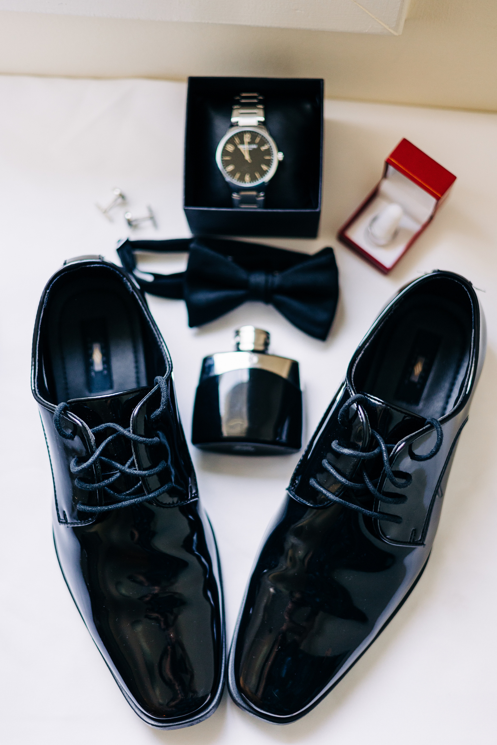 groom wedding detail flat lay featuring shoes, cologne, watch and tie