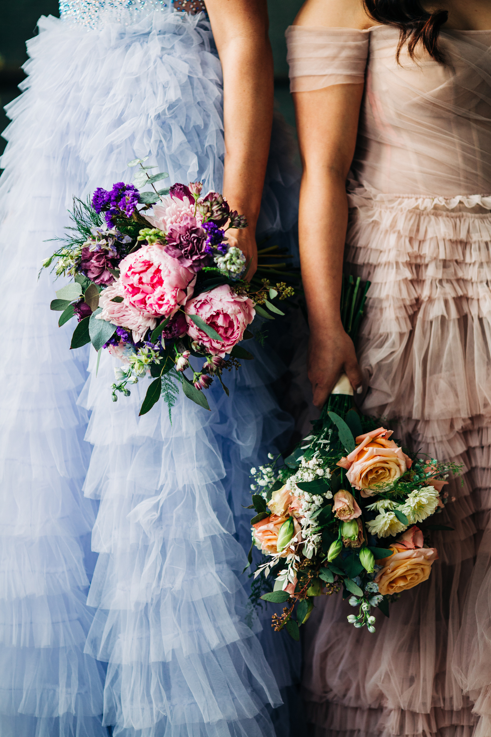 detail photo of two brides with bouquets and colorful texture dresses
