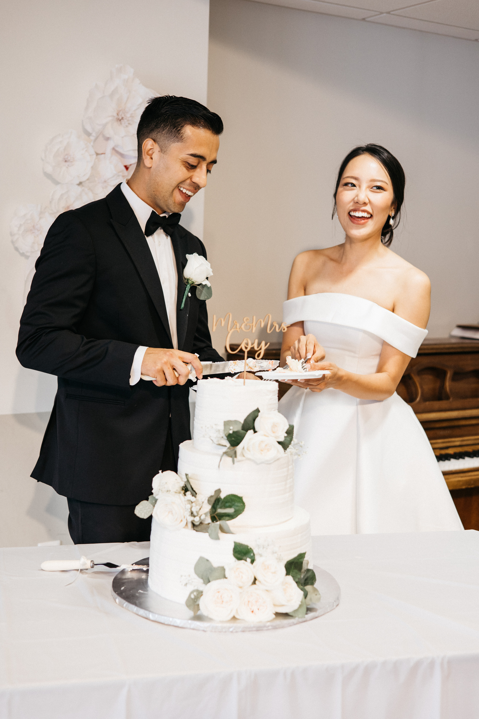 bride and groom laugh while cutting their wedding cake