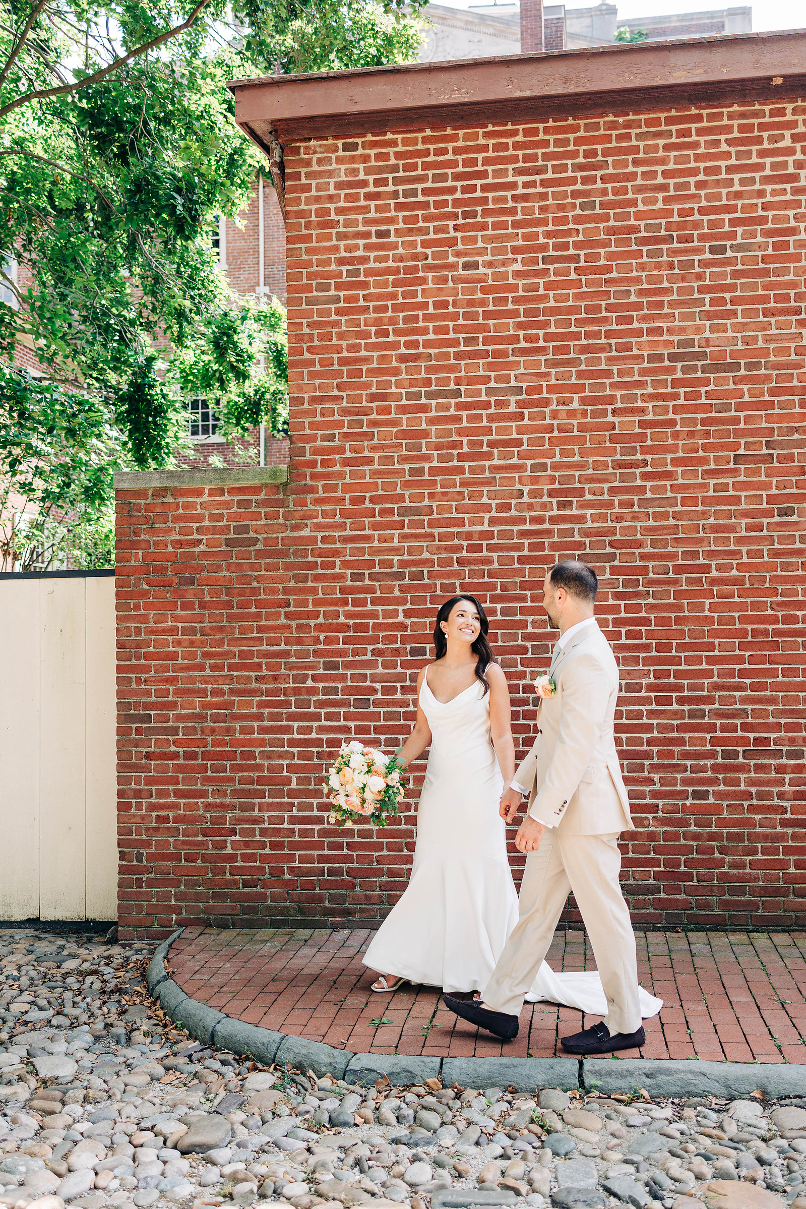 bride and groom walking in old city philadelphia on their wedding day candid wedding photography