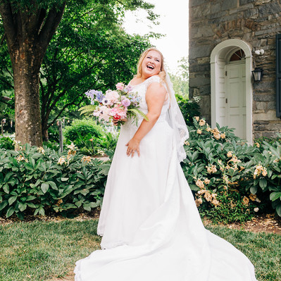 beautiful plus size bride smiling in her wedding gown while holding her bouquet 