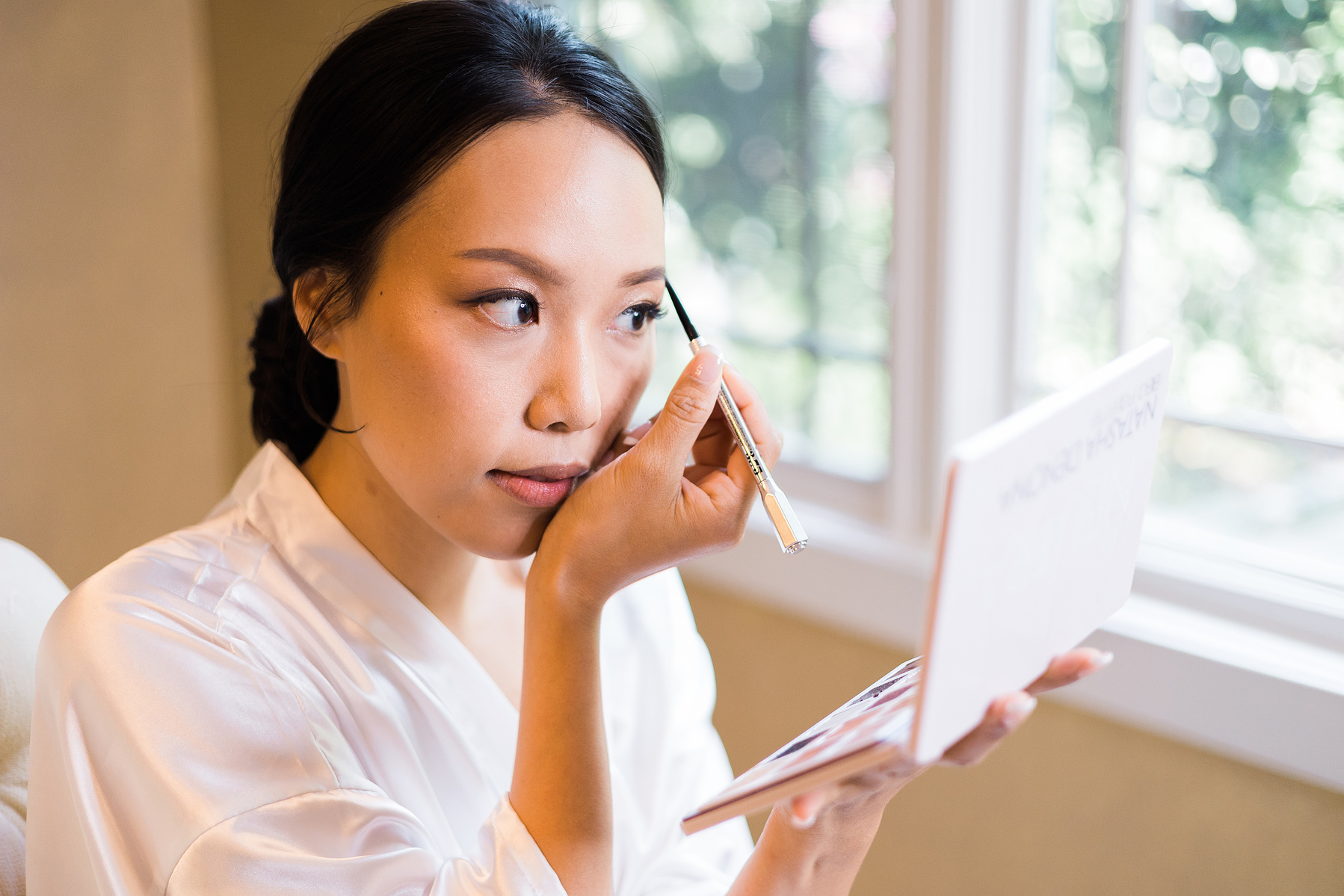 bride applying make up while getting ready for her wedding day 