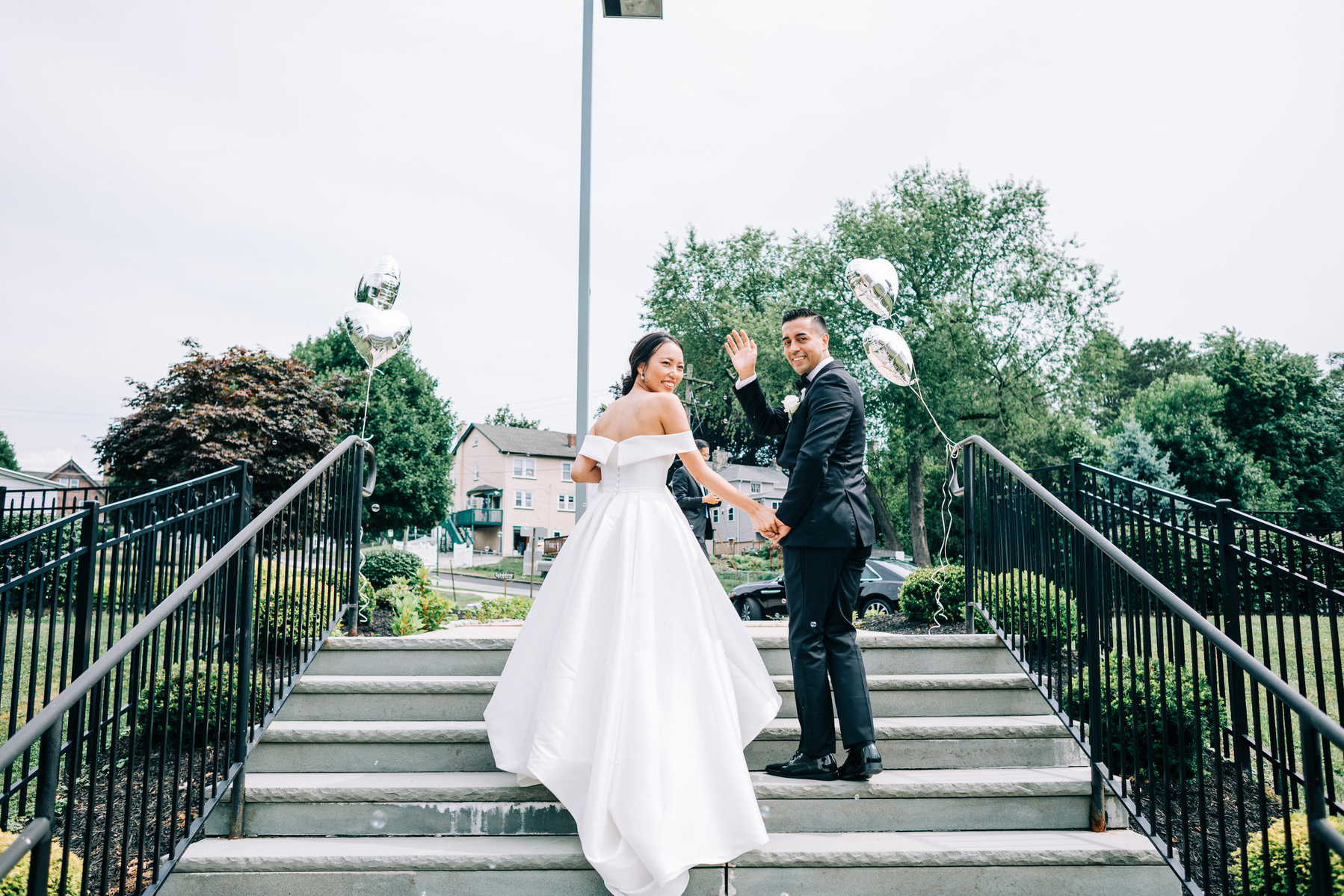 bride and groom look back at their wedding guests and wave while leaving the church after their reception
