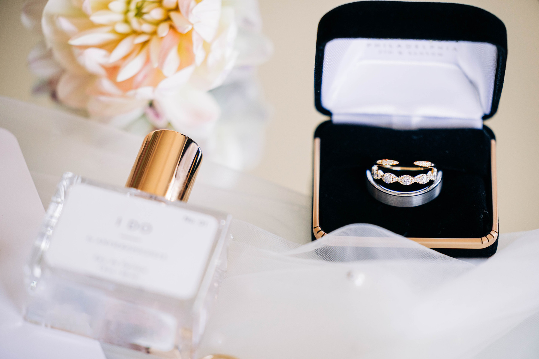 bridal wedding flatlay photography featuring rings, perfume, and florals