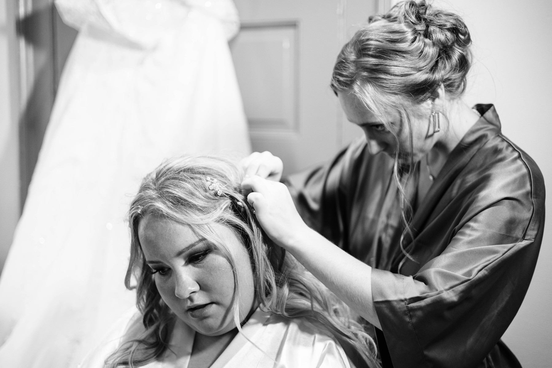 black and white photo of bride getting ready with bridesmaid doing her hair