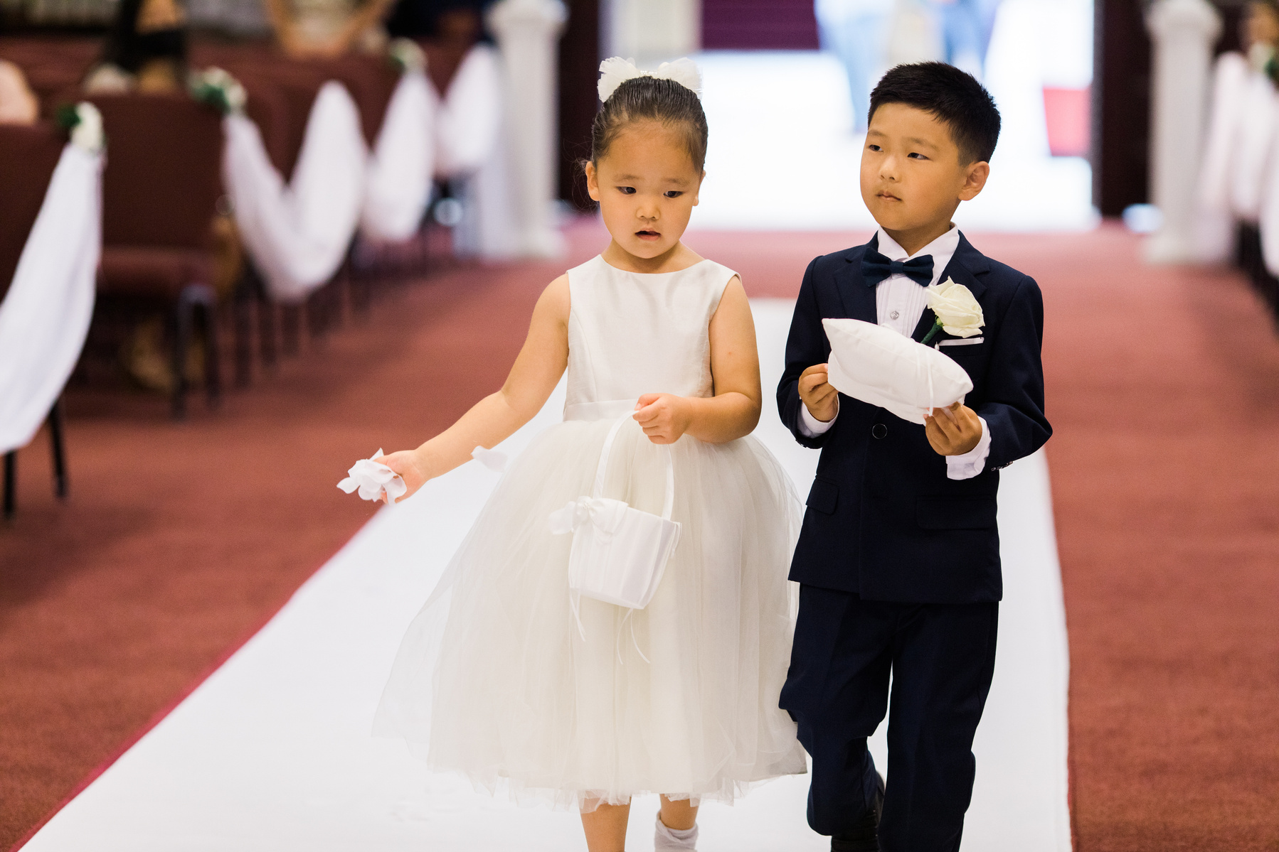 flower girl and ring bearer walking down the wedding aisle in a church