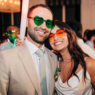 Bride and groom smiling with heart sunglasses and glow sticks during their wedding reception party at the Downtown Club by Cescaphe in Old City Philadelphia