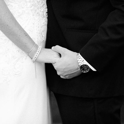 black and white photo of bride and groom holding hands