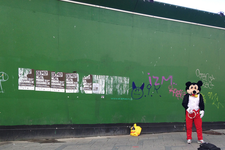 street photography of mickey mouse street performer in Copenhagen, Denmark by green wall