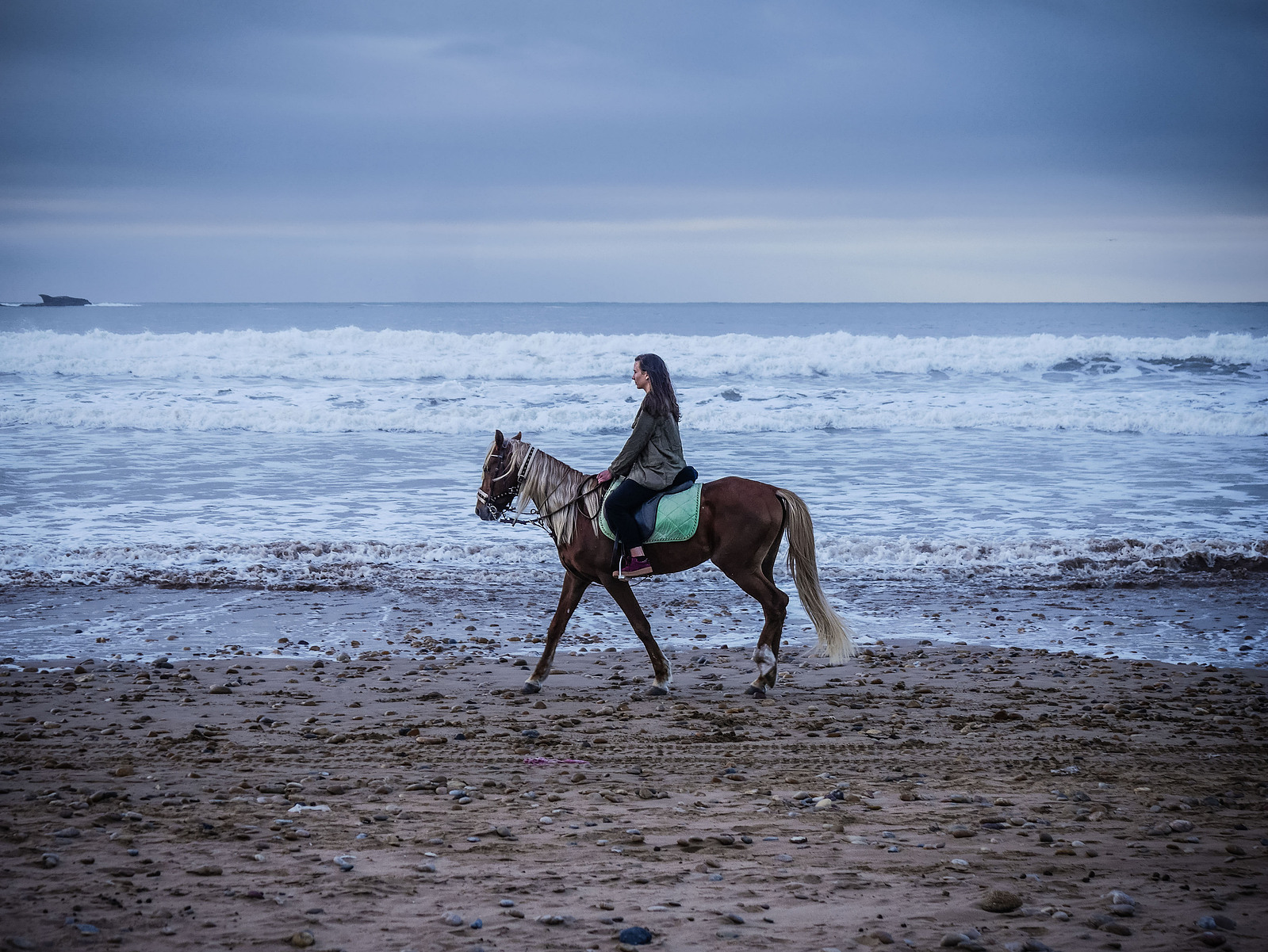 Une femme à cheval au bord de la mer.