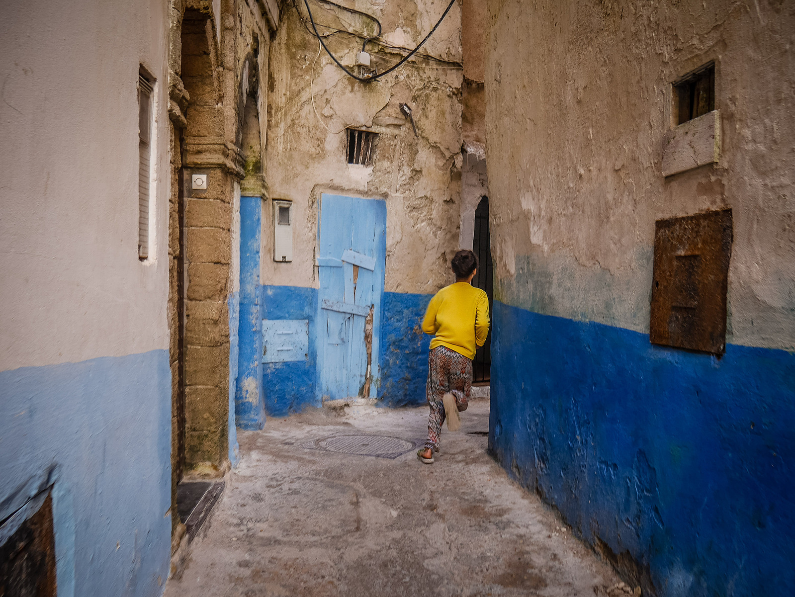 Une petite fille qui court dans une ruelle marocaine.