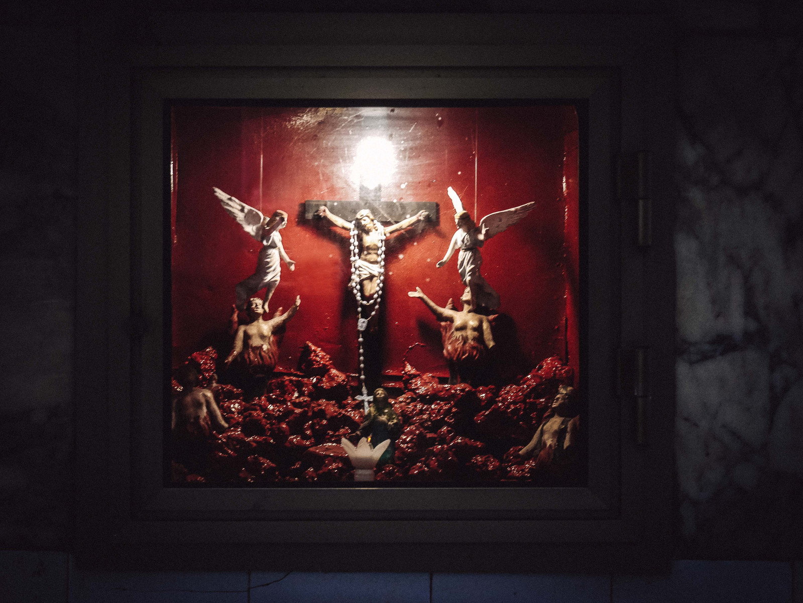 Des crucifie sur fond rouge dans les rues de Naples.