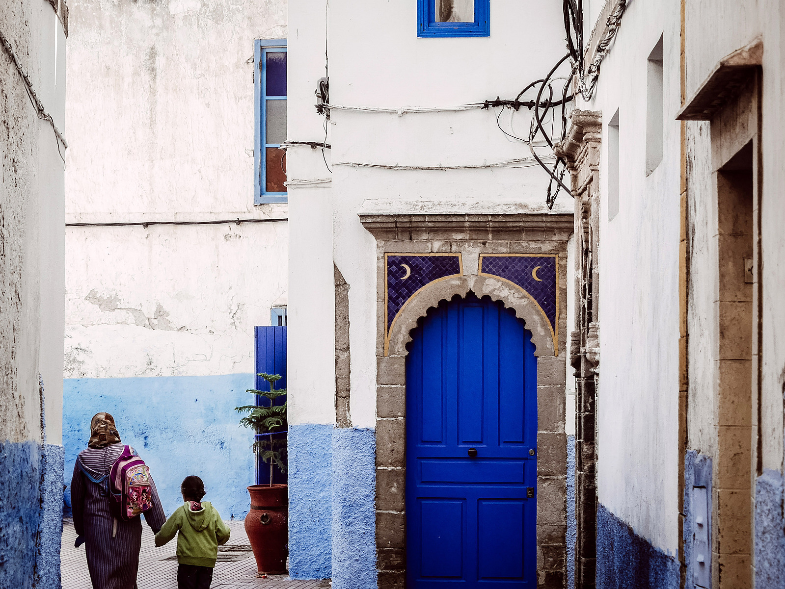 Une mère et son enfant dans une ruelle bleue.
