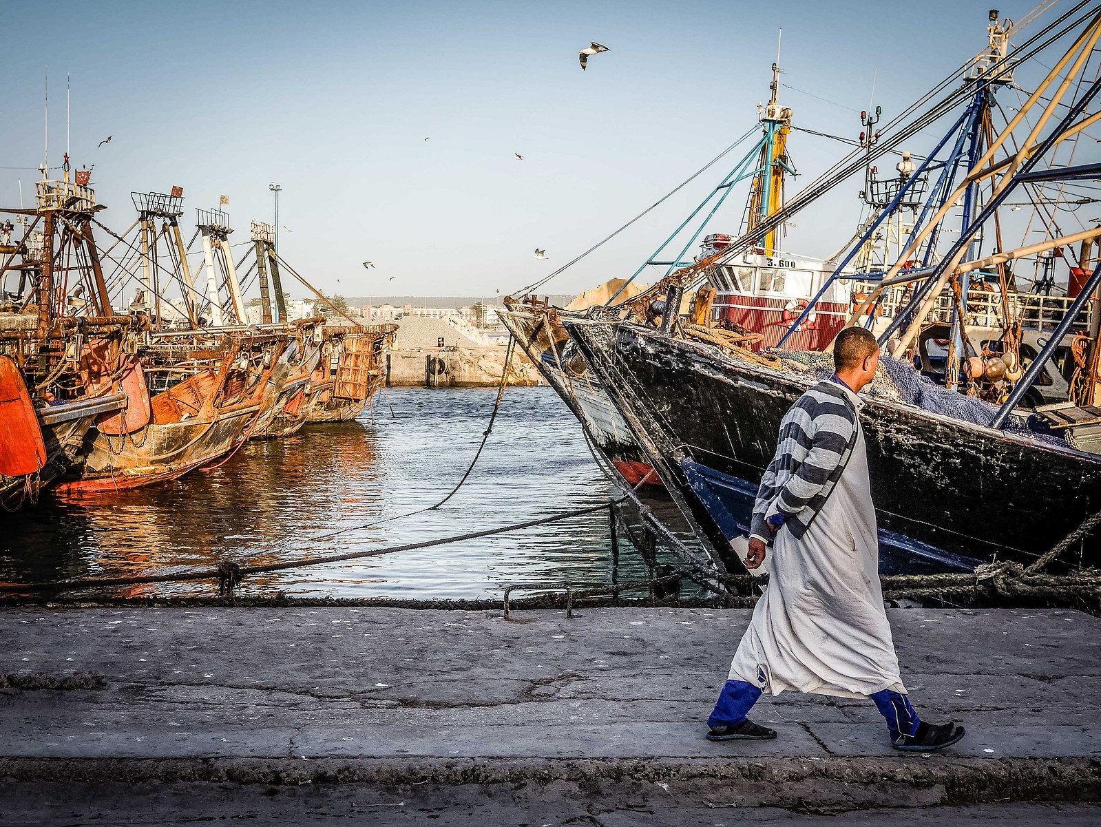Un homme marche sur le quai du port d'Essaouira.