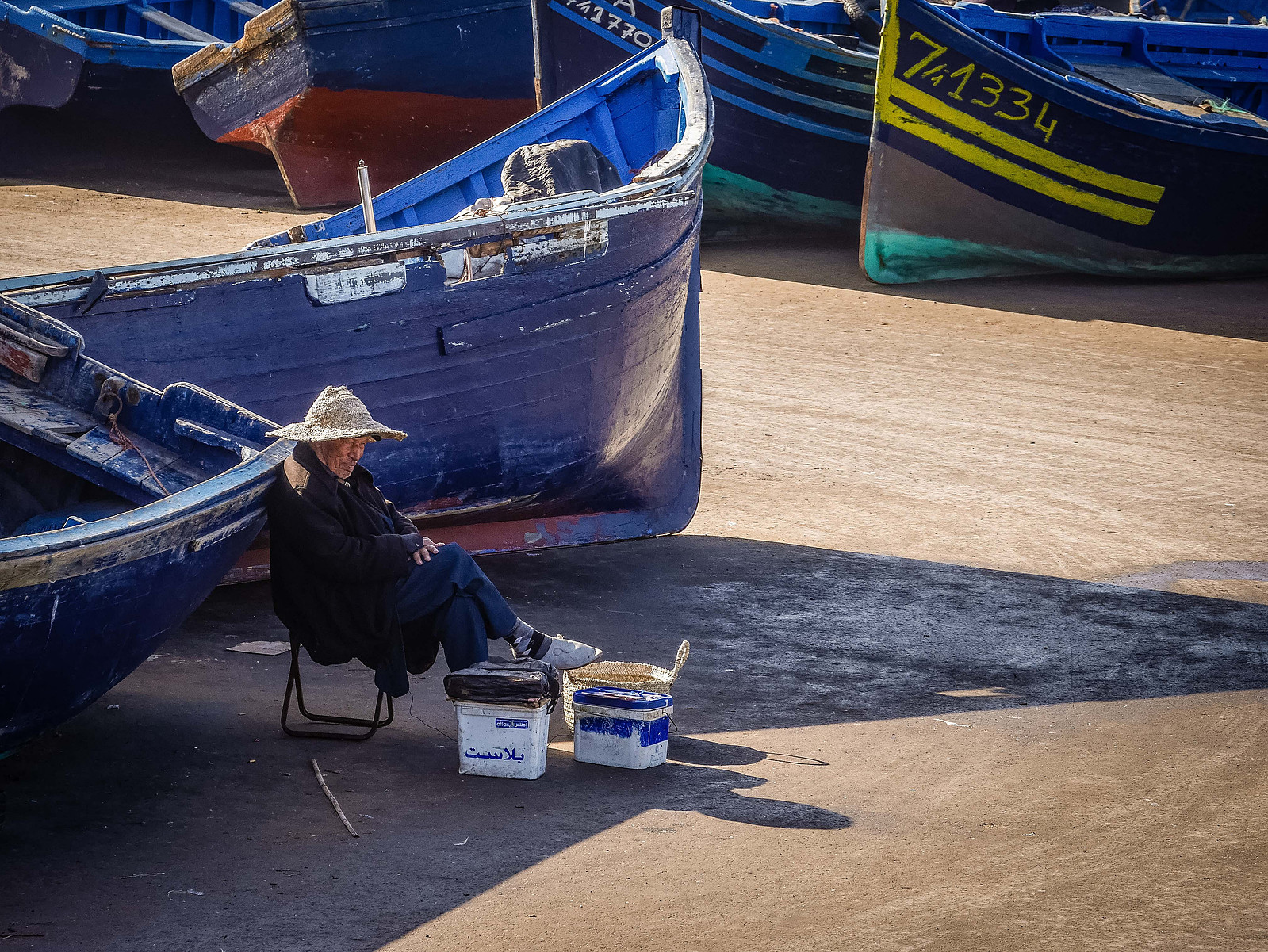 Un homme assis dans un port de pêche.