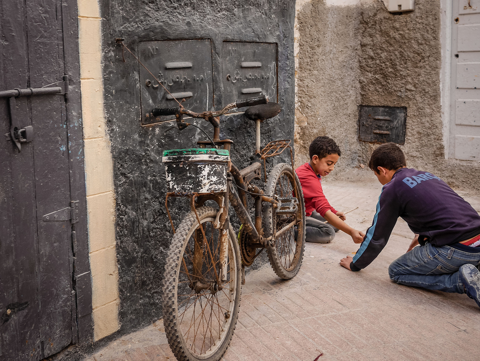 Des enfants qui jouent par terre dans une rue.
