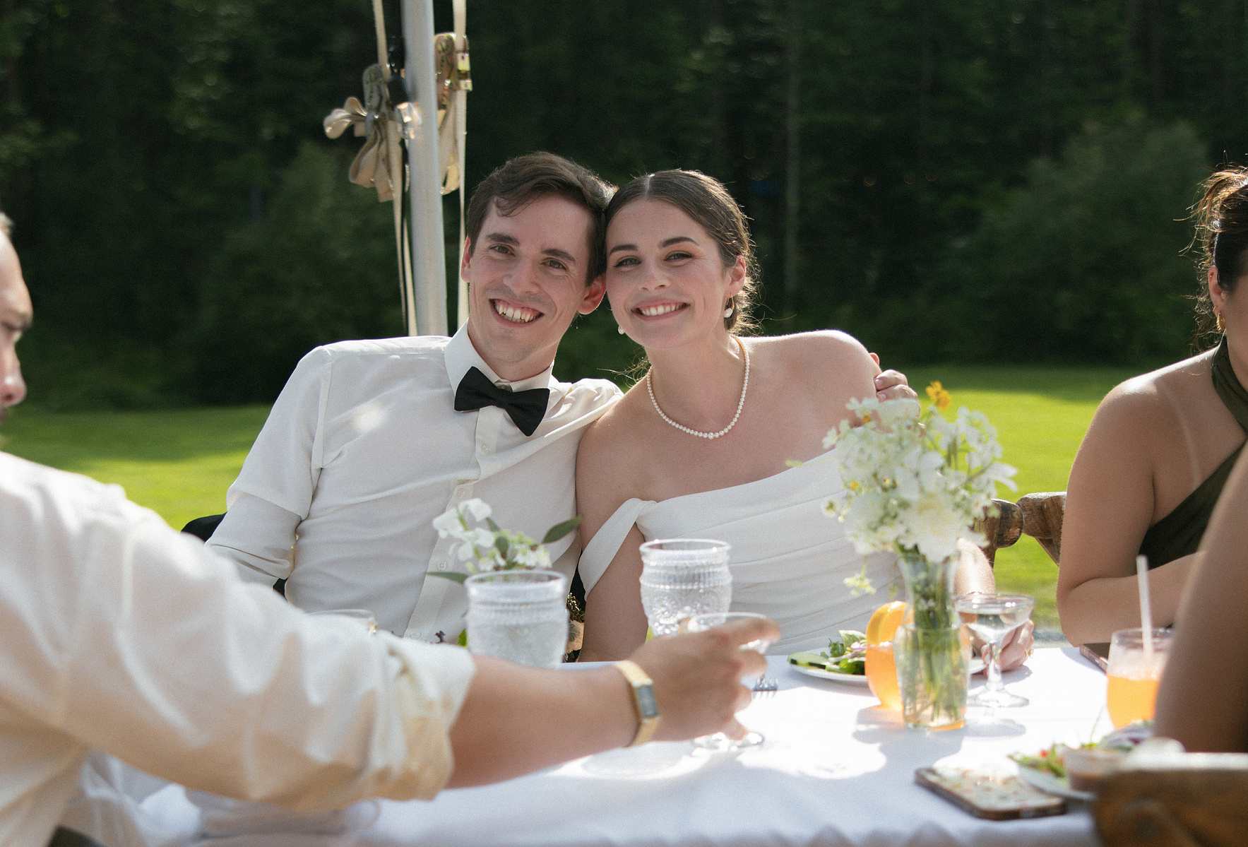 Bride and grooming smiling together for a photo at their table. 