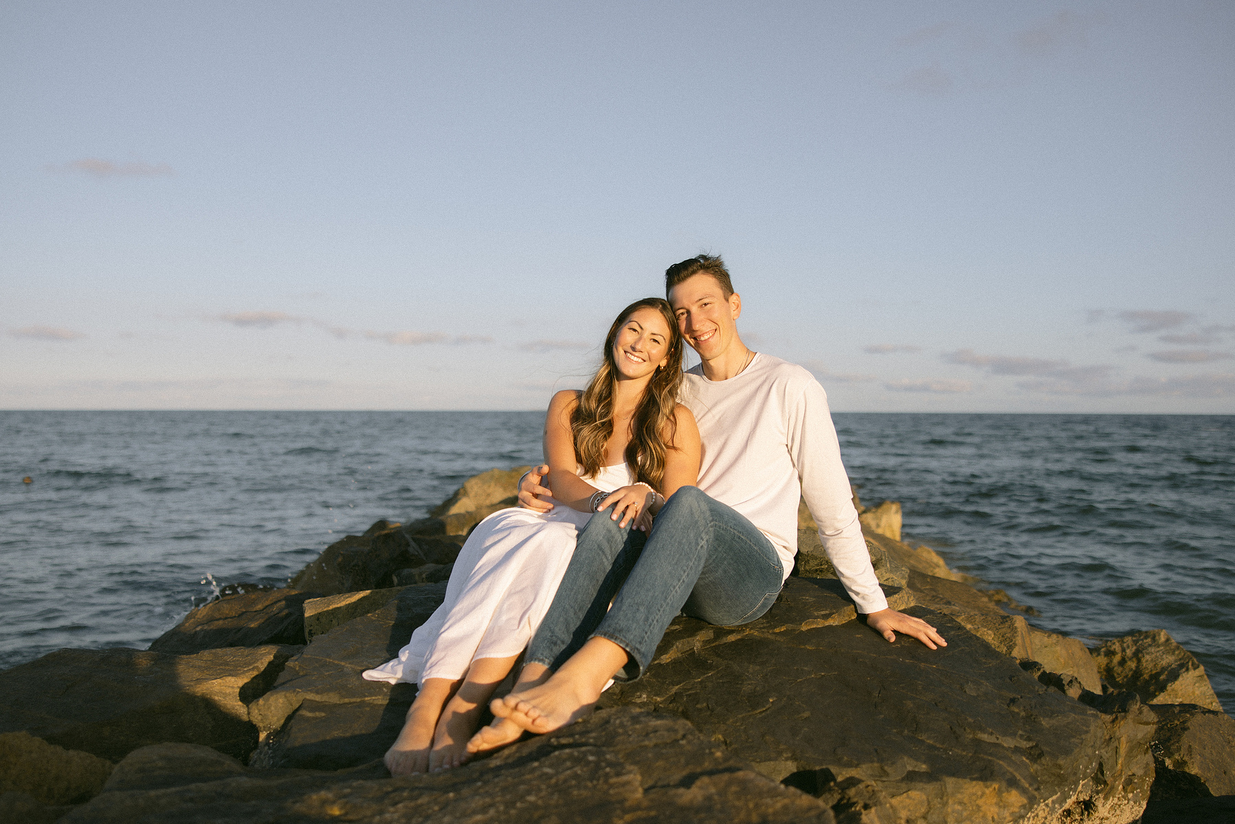 Bride and groom swooning over eachother on the rocks at the beach. 