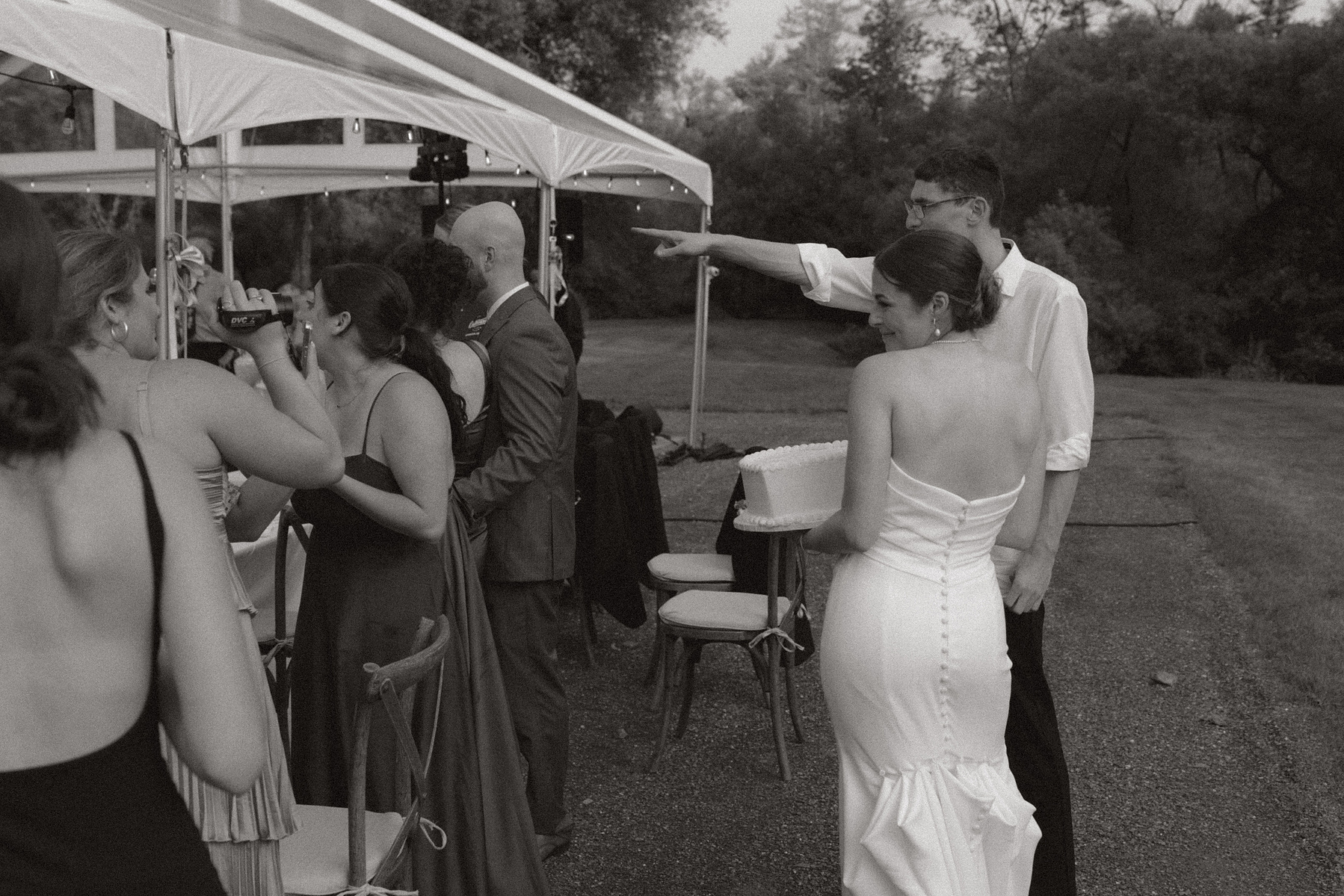 Bride and groom holding their caking posing for their friends photos. 