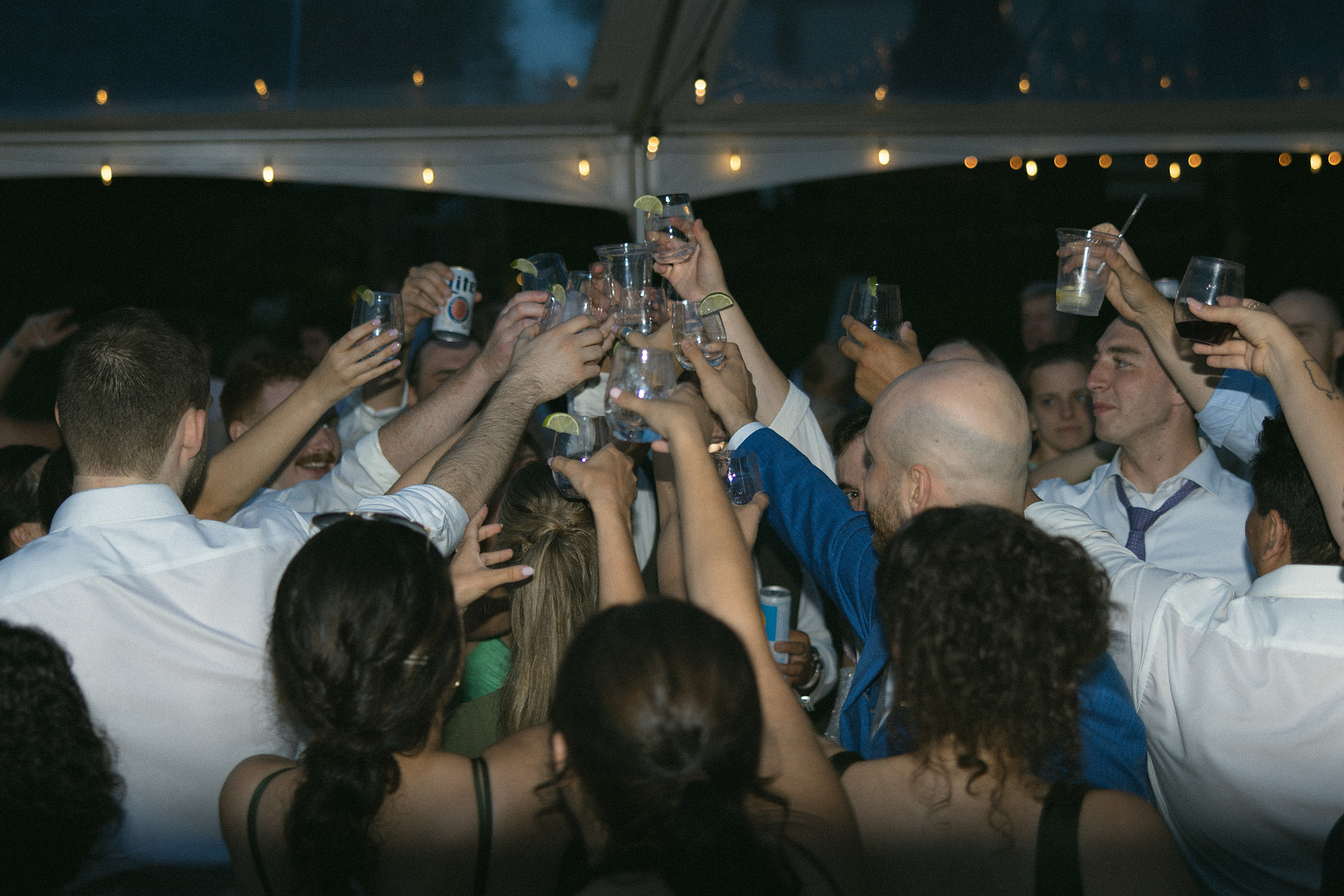 Crowd of people dancing on the dance floor cheering together. 