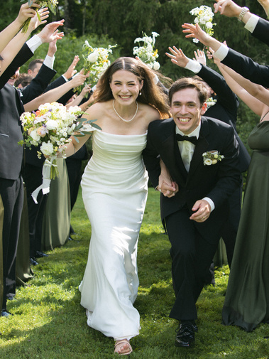 Joyful spring wedding in Vermont, captured by Carson Holmes Photography, a luxury wedding photographer, featuring the bride and groom celebrating with their bridal party amidst blooming florals, lush greenery, and soft pastel tones. New England wedding.