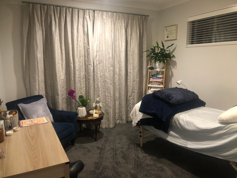 treatment room for reflexology, desk, chair, treatment bed and orchid plant
