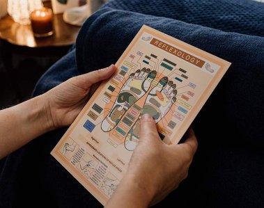 person reading reflexology chart with blue blanket behind in relaxing environment