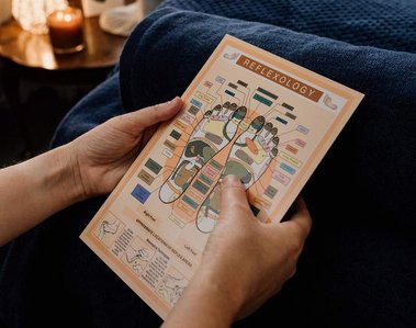 person reading reflexology chart with blue blanket behind in relaxing environment