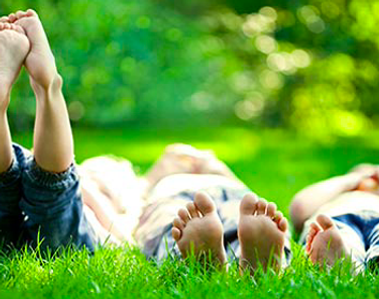 three kids feet lying on the grass on their backs