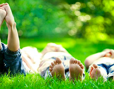 three kids feet lying on the grass on their backs