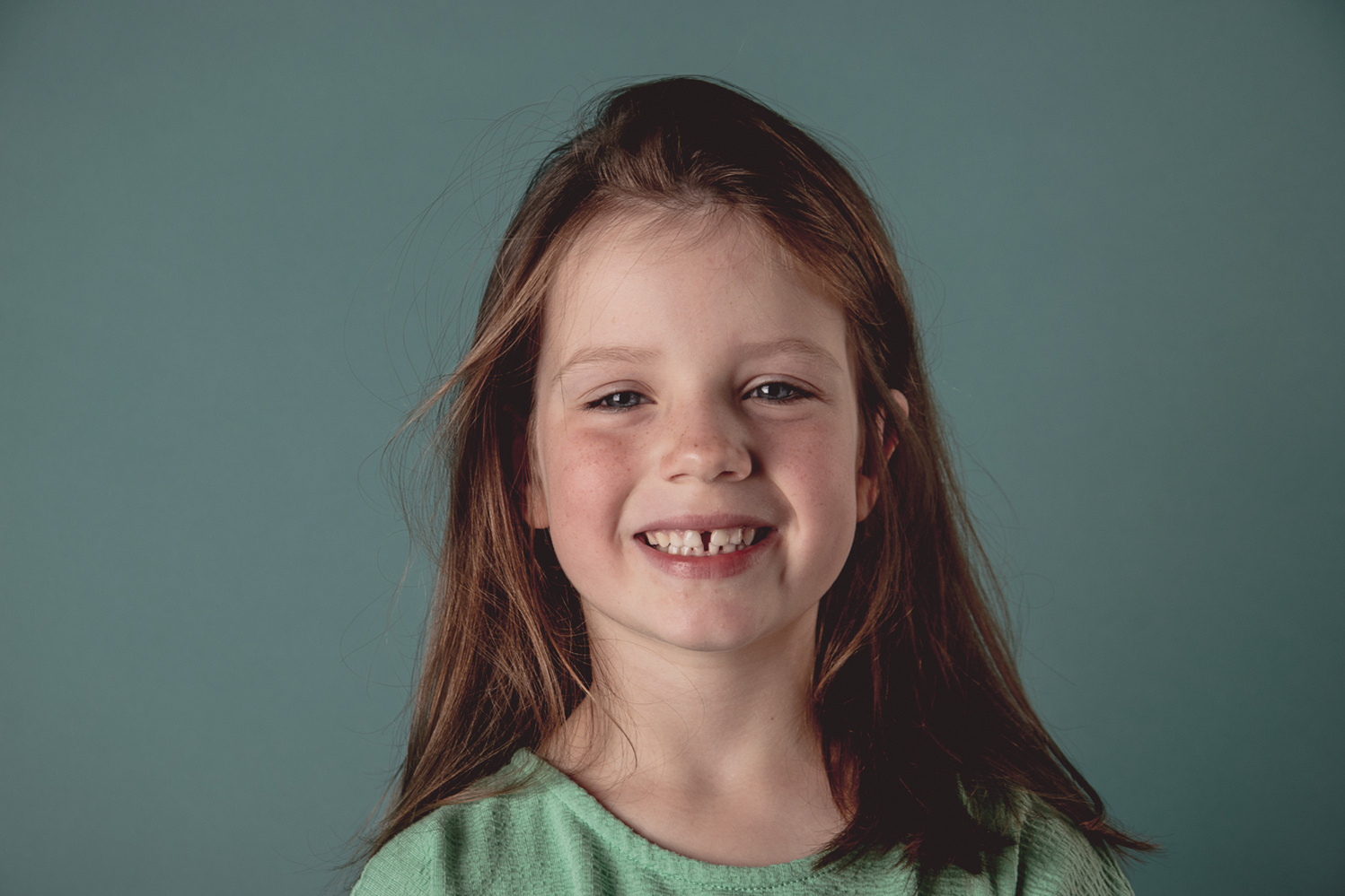 Spontaan porttret in levendige kleuren
In dit portret straalt het meisje pure vrolijkheid uit. De speelse energie spat van de foto af, versterkt door de helder