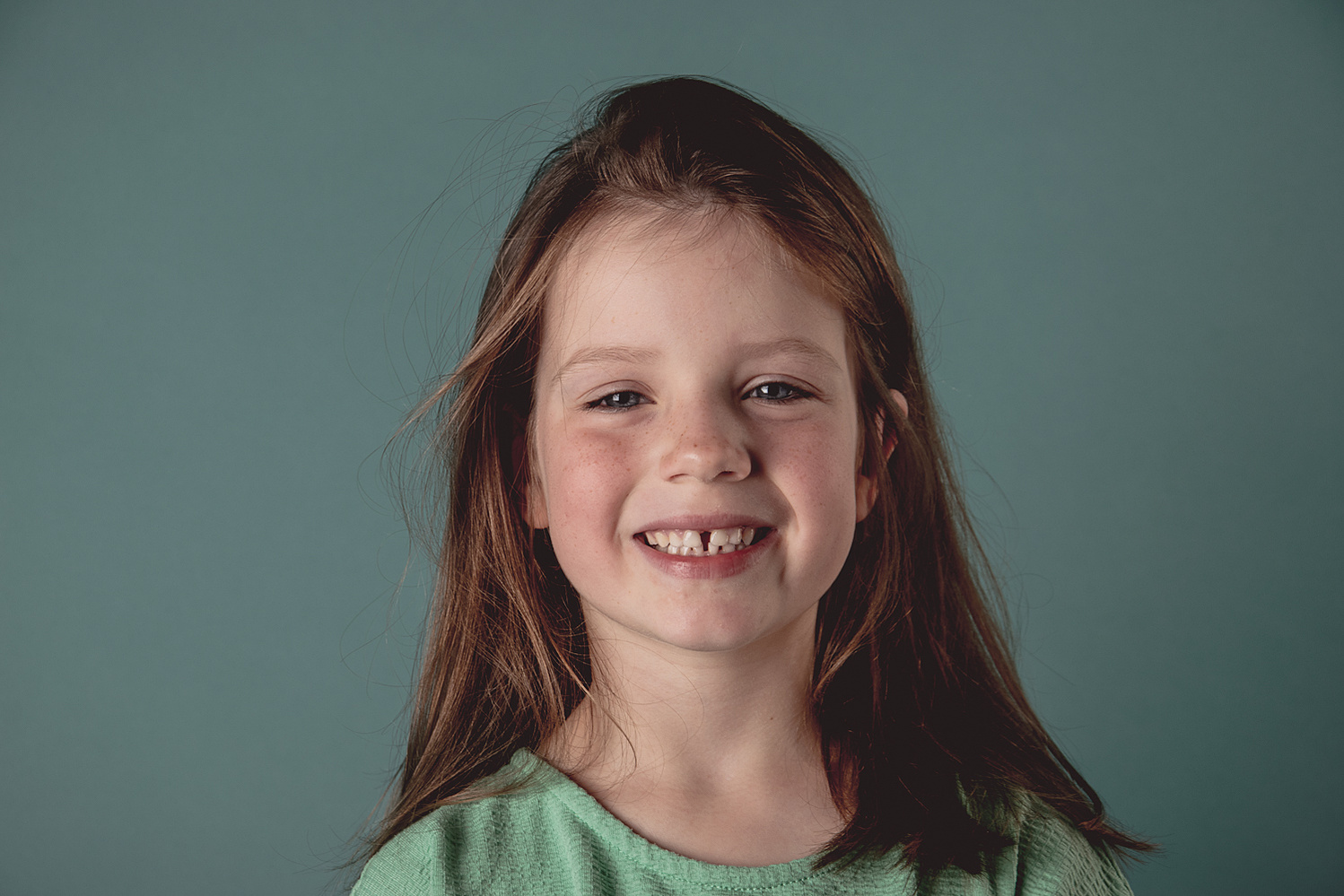 Spontaan porttret in levendige kleuren
In dit portret straalt het meisje pure vrolijkheid uit. De speelse energie spat van de foto af, versterkt door de helder
