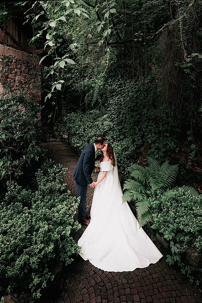 Ein Brautpaar küsst sich im Garten des Gutshof Lana. Hochzeitsfotograf in Suedtirol.