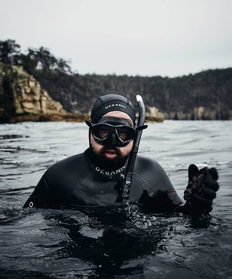 Scuba diver in water holding abalone in Tasmania by Lifestyle Photographer Nic Gossage