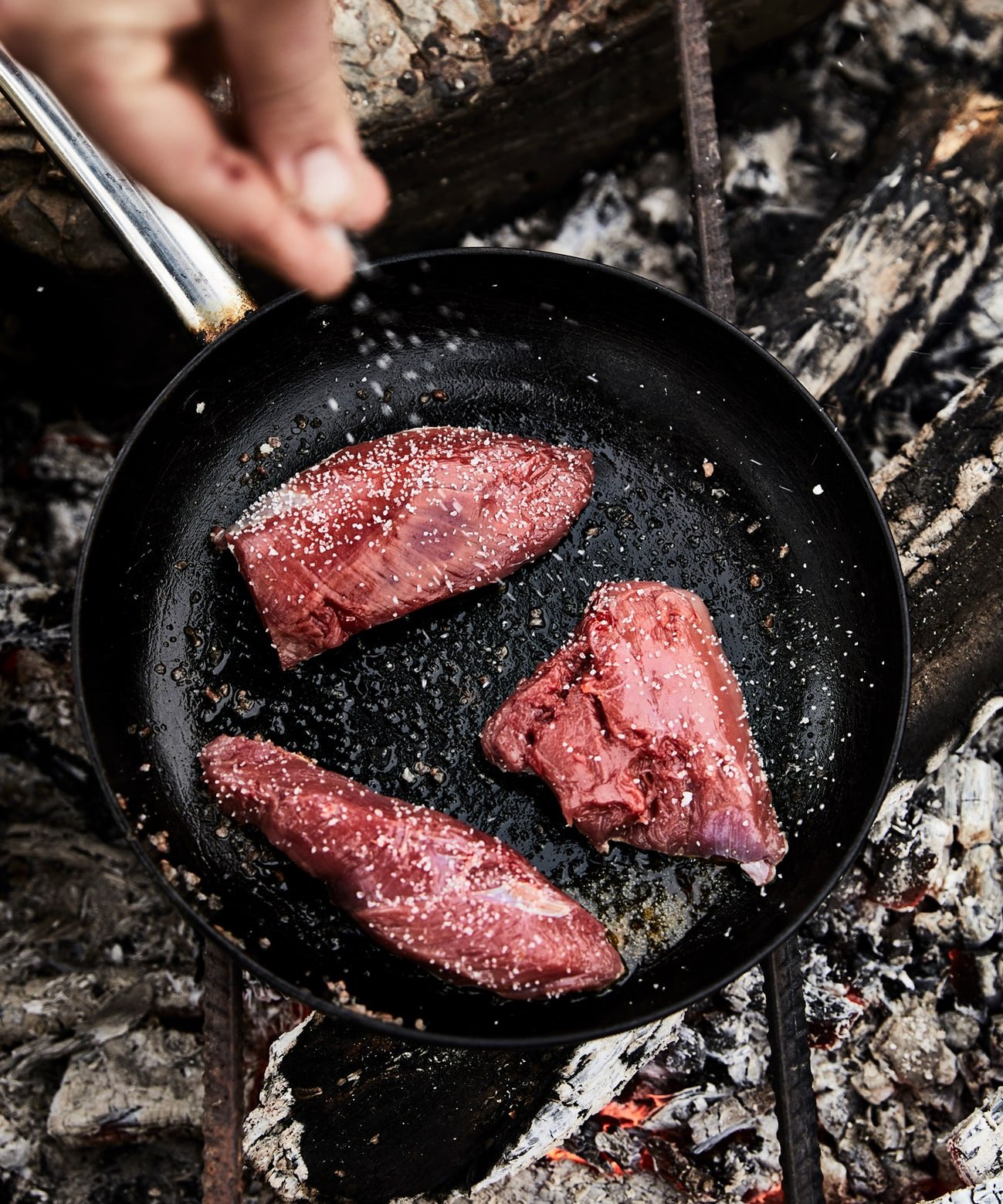 Wallaby on coals being salted and cooked photographed by Food photographers Nic Gossage