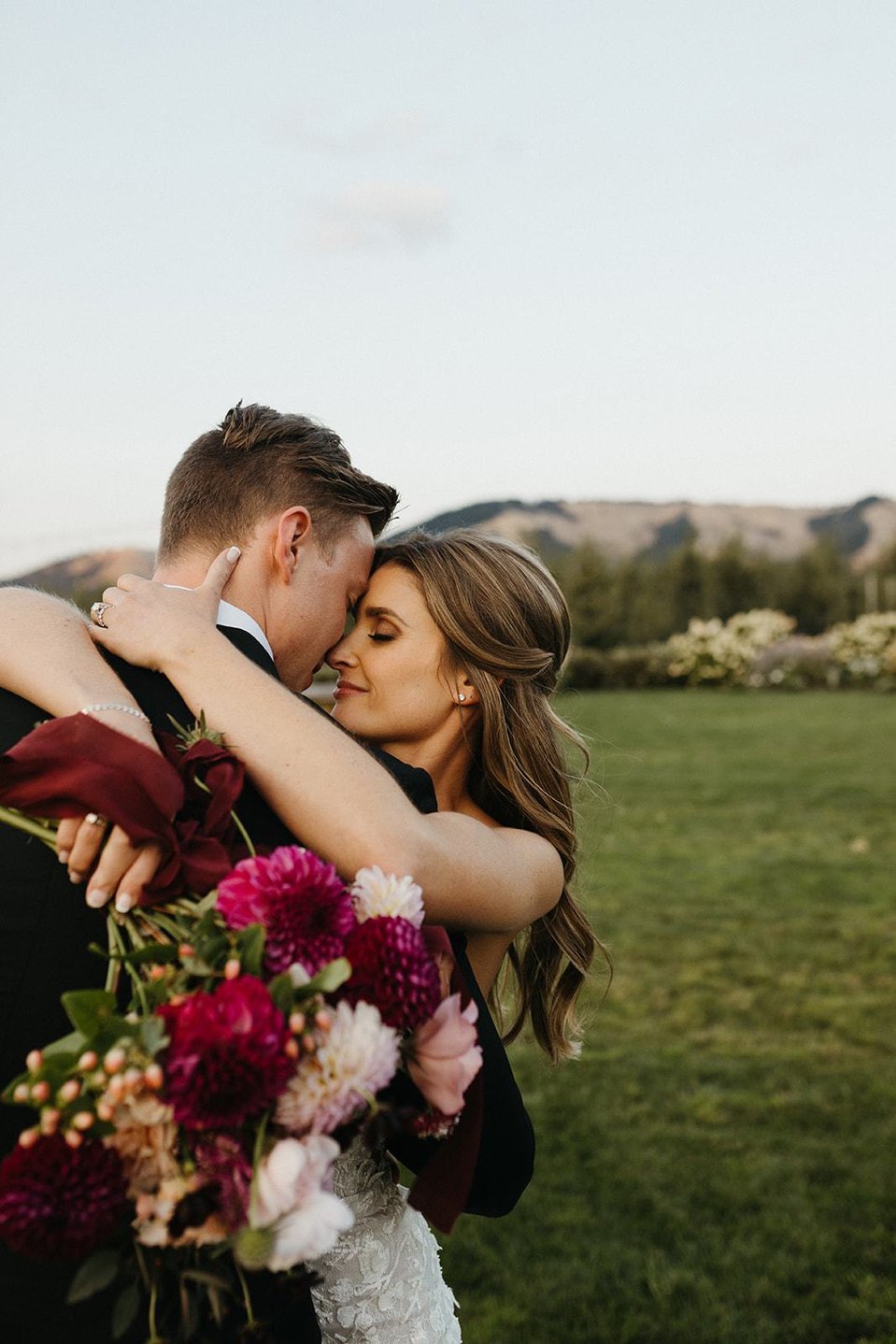 Beautiful bride hugging groom and holding a flowern bouquet. 