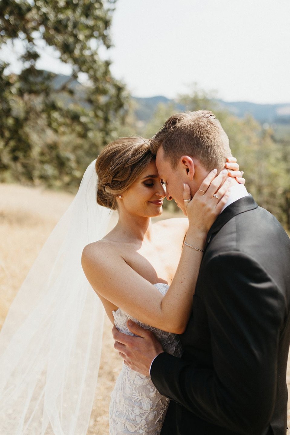Bride with classic wedding bridal updo holding groom's face.