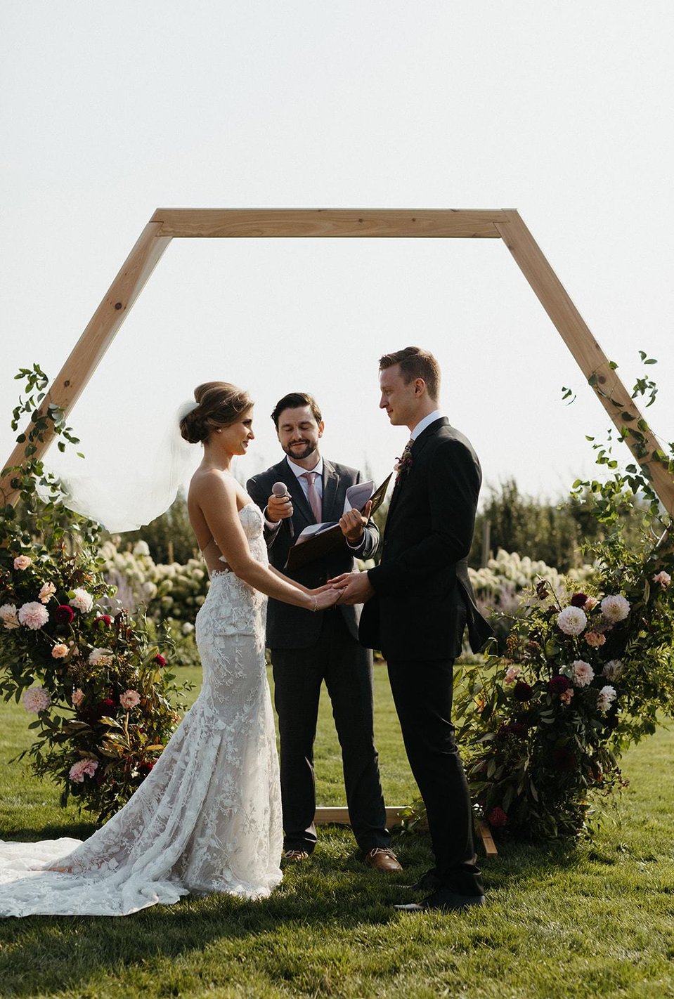 The bride and groom hold hands during the ceremony with elegant hair updo. 