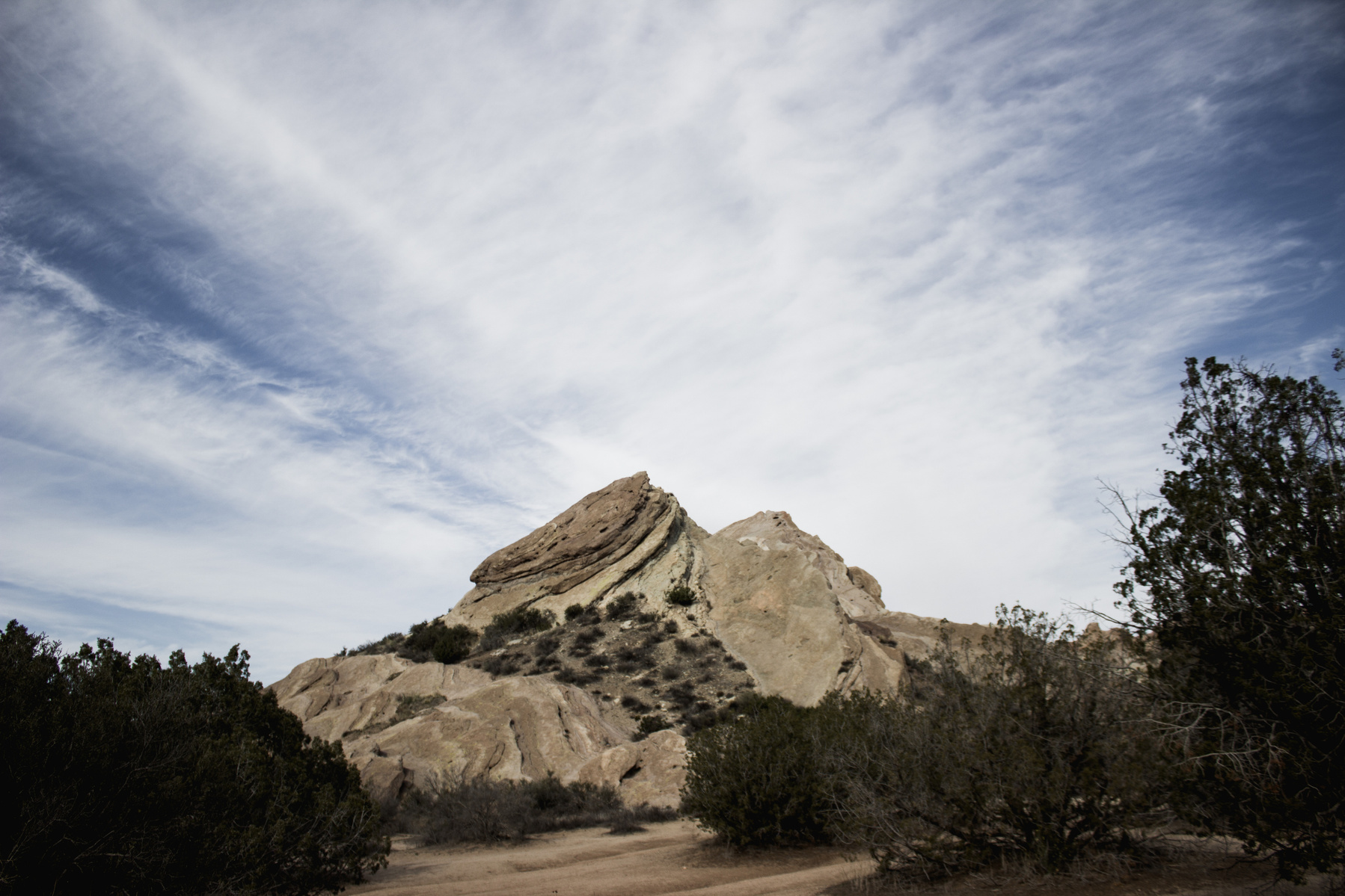 Center rock formation with sky in background and trees in foreground